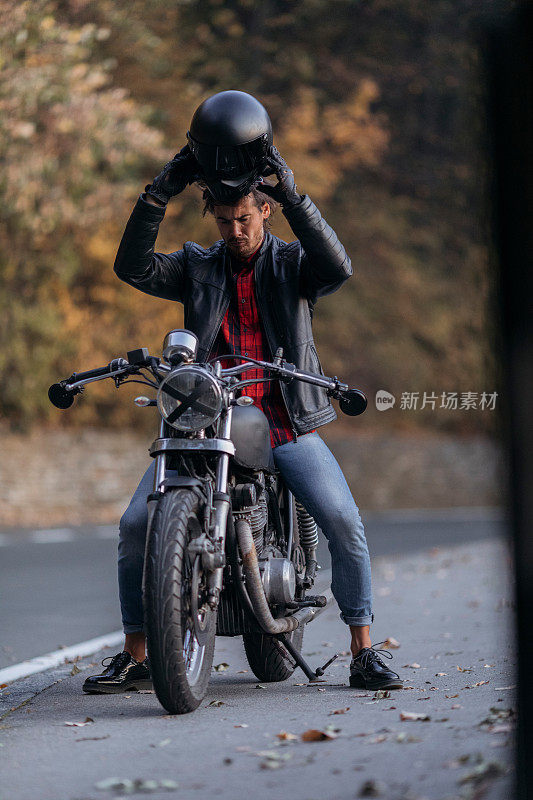 Handsome Caucasian male biker mounting his motorbike